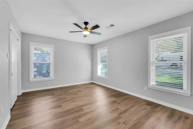 a view of an empty room with wooden floor and a window