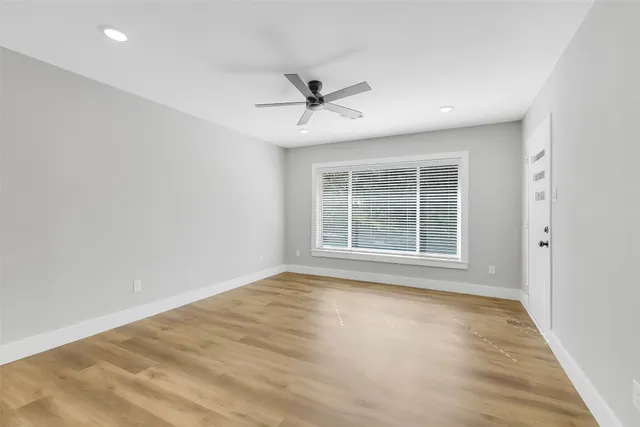 an empty room with wooden floor and windows