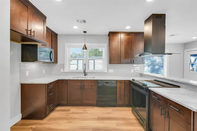 a kitchen with stainless steel appliances granite countertop a sink and stove top oven with wooden floor