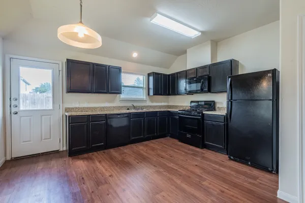 a kitchen with stainless steel appliances granite countertop a refrigerator a sink dishwasher a stove with wooden cabinets and wooden floor