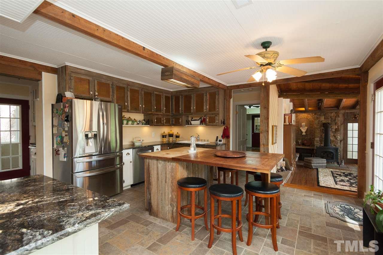 7018 Farmdale Road Raleigh, NC 27610 - Photo 18 of 25 a kitchen with stainless steel appliances kitchen island granite countertop a table chairs in it and wooden floors