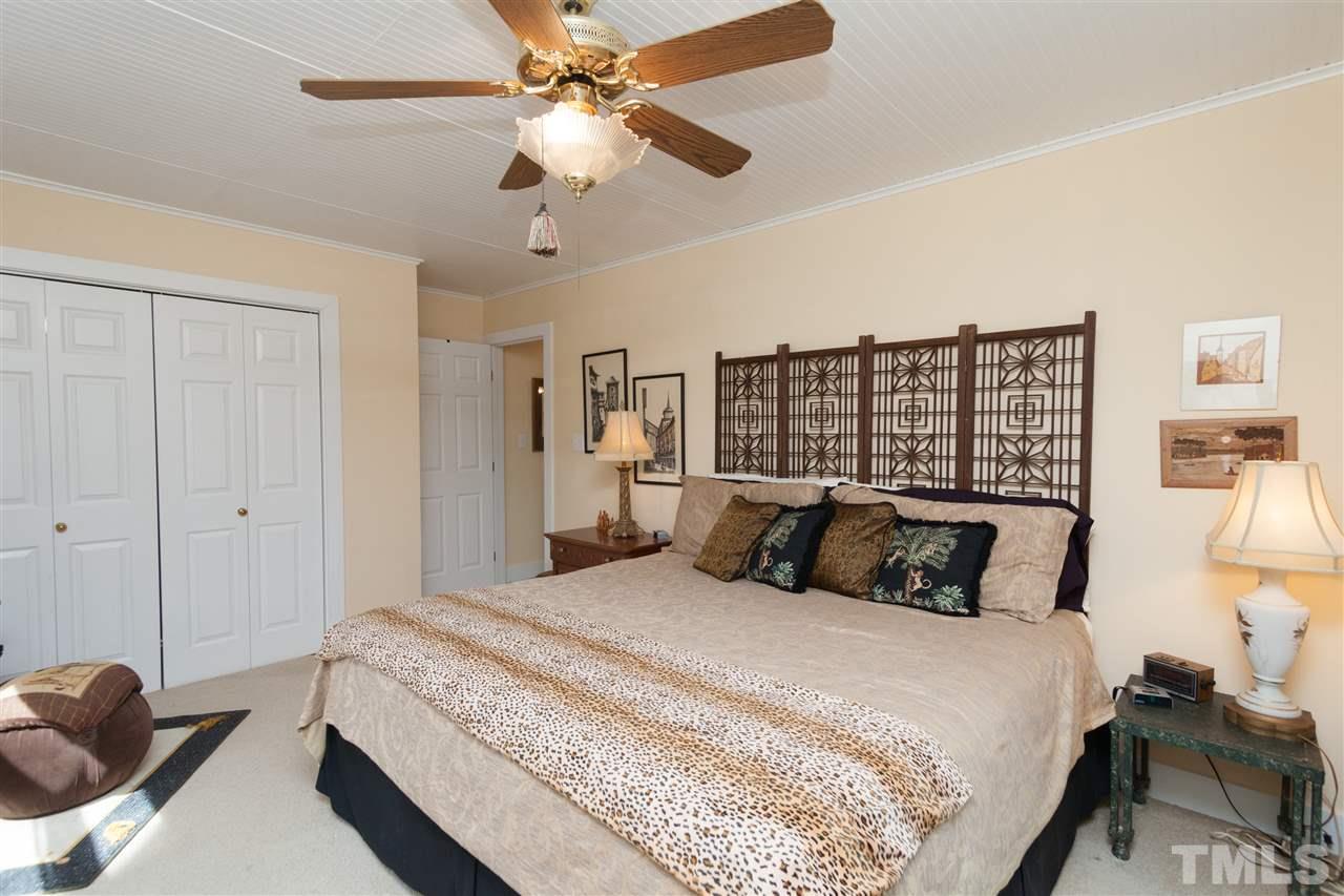 7018 Farmdale Road Raleigh, NC 27610 - Photo 22 of 25 a bedroom with a large bed and a chandelier