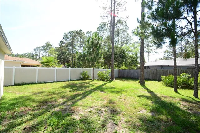 a backyard of a house with plants and wooden fence