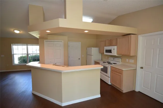 a kitchen with stainless steel appliances wooden floors and white cabinets