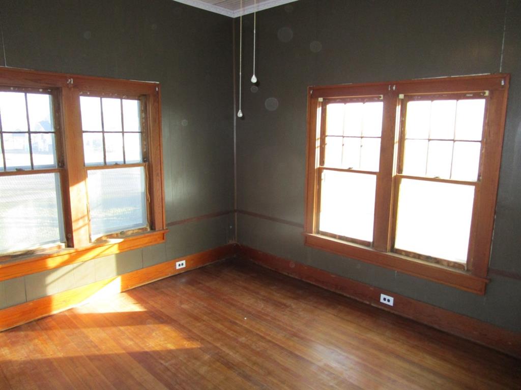 1206 South Main Street Quanah, TX 79252 - Photo 12 of 22 Unfurnished room featuring plenty of natural light, baseboards, and wood finished floors