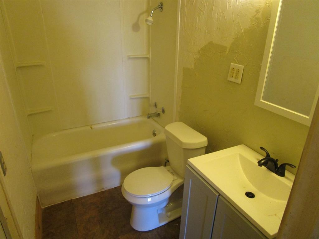 1206 South Main Street Quanah, TX 79252 - Photo 15 of 22 Full bathroom featuring toilet, vanity, and bathtub / shower combination
