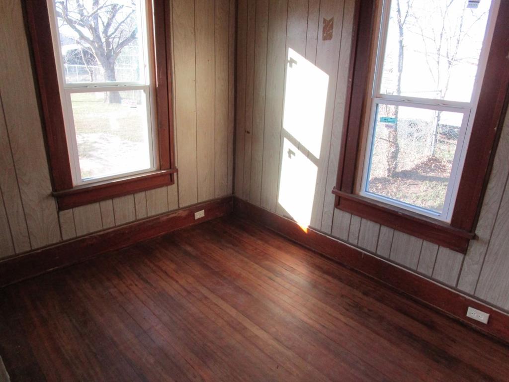 1206 South Main Street Quanah, TX 79252 - Photo 19 of 22 Spare room with wooden walls and dark wood-style flooring