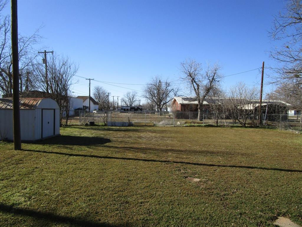 1206 South Main Street Quanah, TX 79252 - Photo 5 of 22 View of yard with a storage shed, fence, and an outbuilding