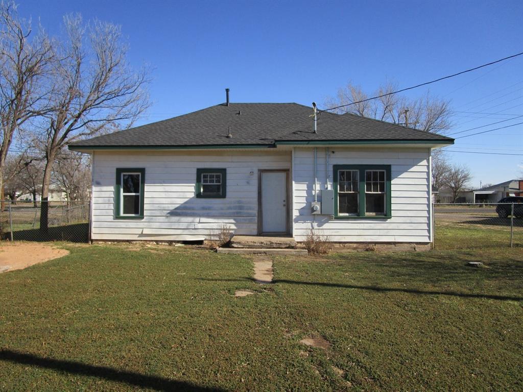 1206 South Main Street Quanah, TX 79252 - Photo 8 of 22 Rear view of house with a lawn, roof with shingles, and fence
