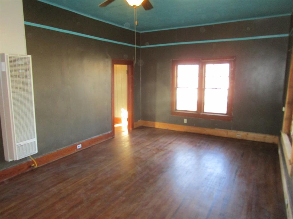 1206 South Main Street Quanah, TX 79252 - Photo 10 of 22 Spare room with a heating unit, baseboards, and wood finished floors