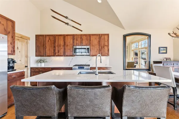 a kitchen with kitchen island granite countertop a table chairs sink and cabinets