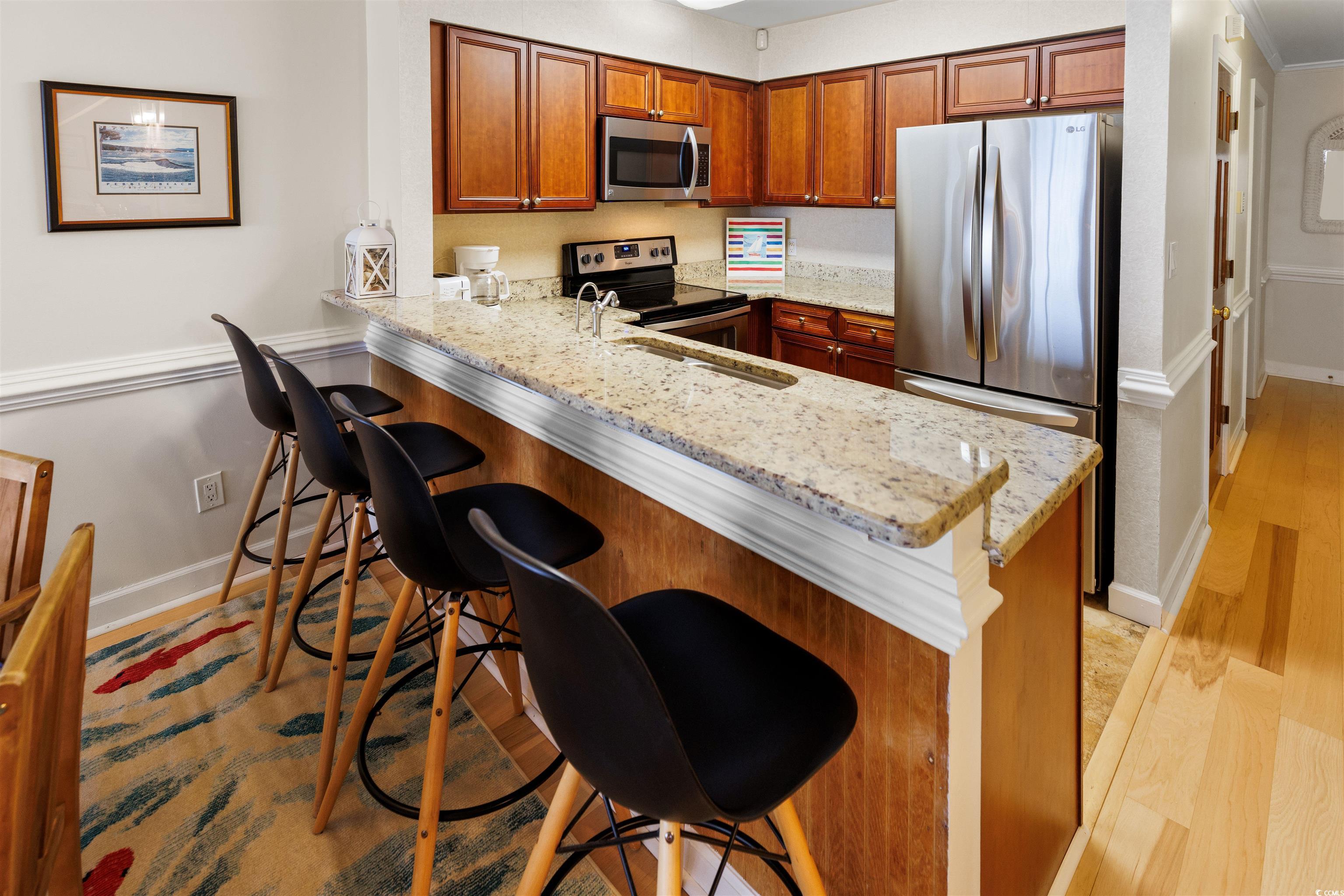 320 North Waccamaw Drive, Unit 3B Murrells Inlet, SC 29576 - Photo 3 of 15 Kitchen featuring a breakfast bar, appliances with stainless steel finishes, light stone counters, and a peninsula