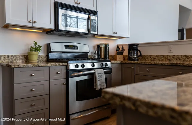 a kitchen with granite countertop a stove and cabinets