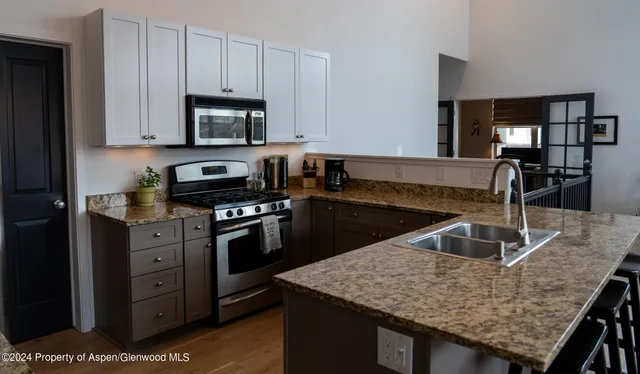 a kitchen with granite countertop a sink dishwasher and stove with wooden floor