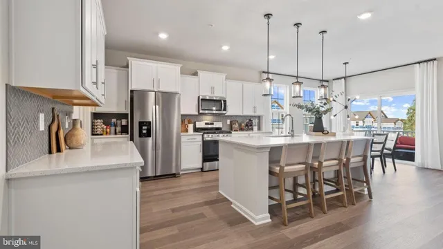 a kitchen with stainless steel appliances granite countertop a refrigerator a stove top oven a refrigerator a sink and a dining table with wooden floor