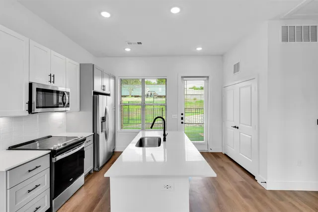 a kitchen with stainless steel appliances granite countertop a sink a stove a refrigerator a window