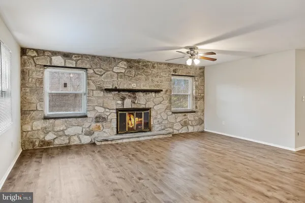 an empty room with windows fireplace and a kitchen view