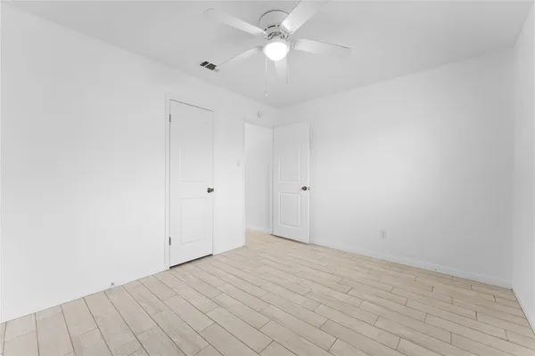 an empty room with a ceiling fan and window