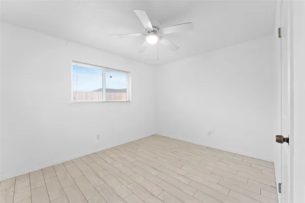 a view of a room with wooden floor and a ceiling fan