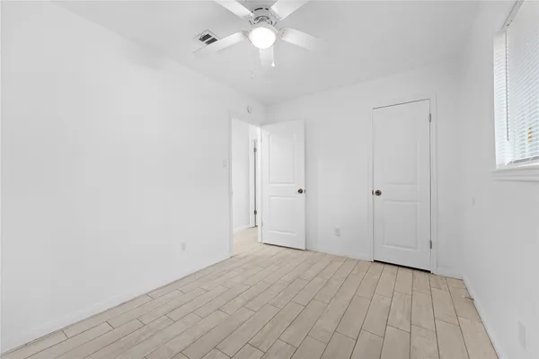 an empty room with a window and a fan