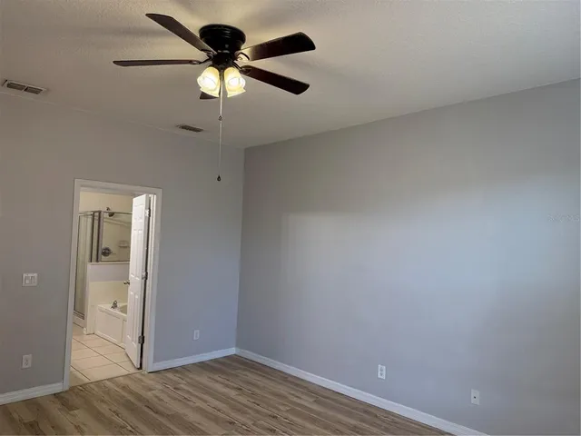 a view of room with hardwood floor and a ceiling fan
