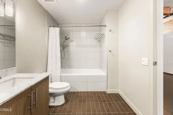 a bathroom with a granite countertop bathtub shower sink vanity and toilet