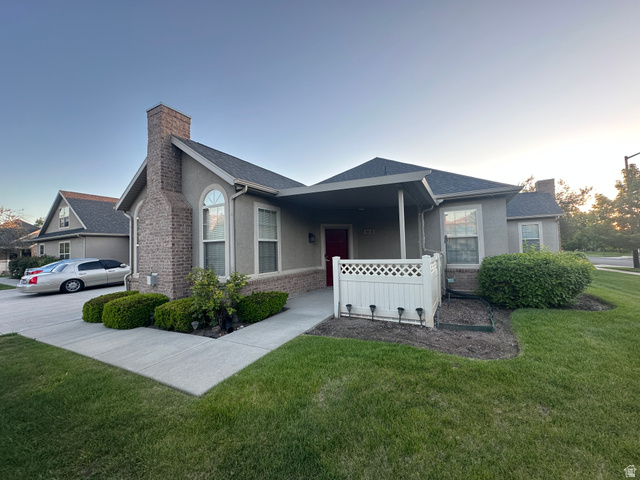 511 West 300 South, Unit B Springville, UT 84663 - Photo 1 of 1 Stucco exterior home featuring a prominent brick chimney, arched window, covered porch entry, white lattice fencing, and a paved driveway