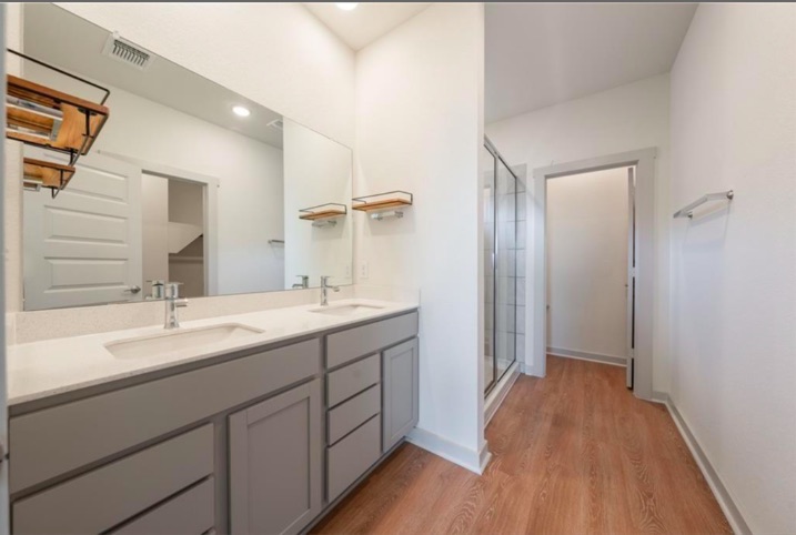 10805 Meris Lane Austin, TX 78754 - Photo 18 of 28 Dual vanities with modern fixtures and a spacious glass-enclosed shower create a functional primary bathroom.