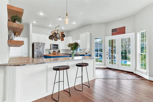 a kitchen with stainless steel appliances granite countertop a stove a sink dishwasher and a dining table with wooden floor