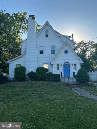 a front view of house with a yard and trees in the background