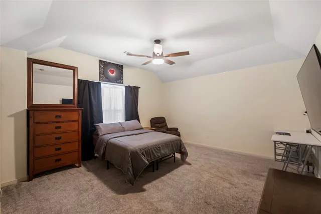 a bedroom with a bed a dresser and a chandelier