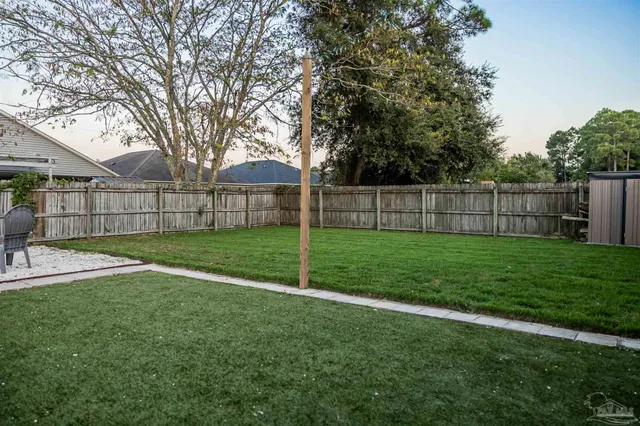 a view of a yard with a large trees and wooden fence