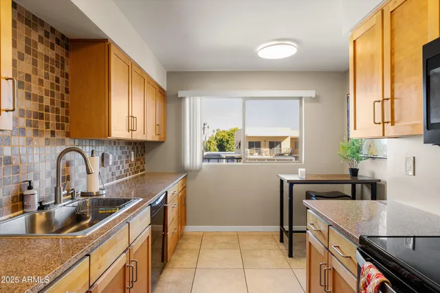 a kitchen with stainless steel appliances granite countertop a sink a stove top oven a refrigerator with grey cabinets and wooden floor