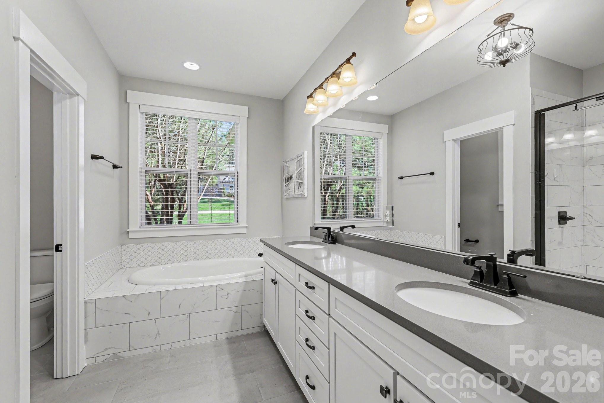 4193 Persimmon Road Lancaster, SC 29720 - Photo 16 of 42 a bathroom with a granite countertop tub a double vanity sink a large mirror and a bathtub next to a window