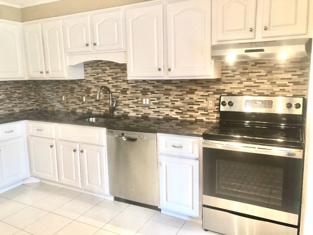 146 Marble Street, Unit 204 Stoneham, MA 02180 - Photo 3 of 21 a kitchen with granite countertop white cabinets and white appliances