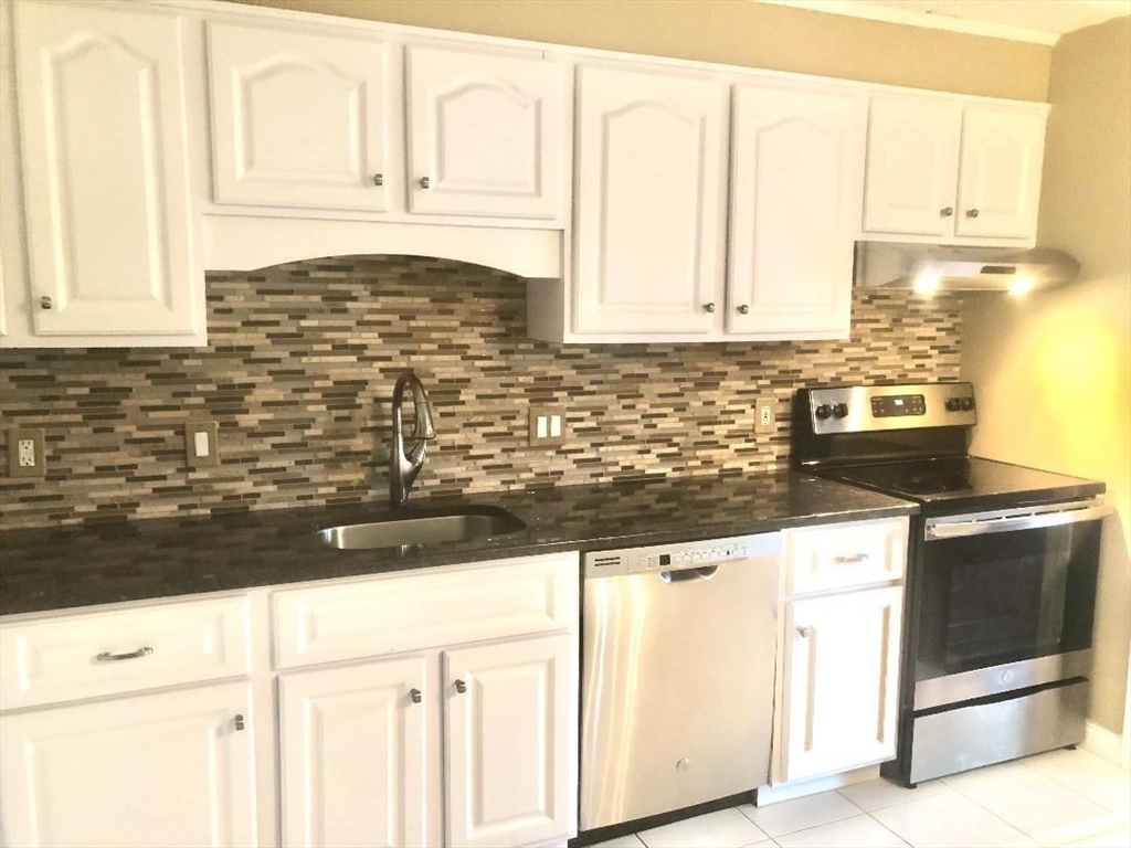 146 Marble Street, Unit 204 Stoneham, MA 02180 - Photo 4 of 21 a kitchen with granite countertop white cabinets and white appliances