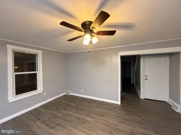 a view of a room with wooden floor and a ceiling fan