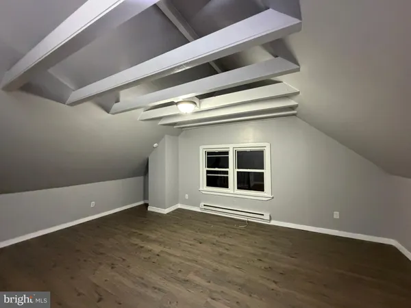 a view of an empty room with wooden floor and windows
