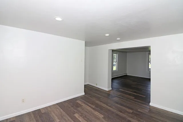 a view of an empty room with wooden floor and closet