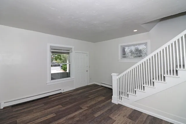 a view of a hallway with wooden floor and windows