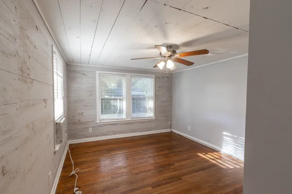 an empty room with wooden floor and windows