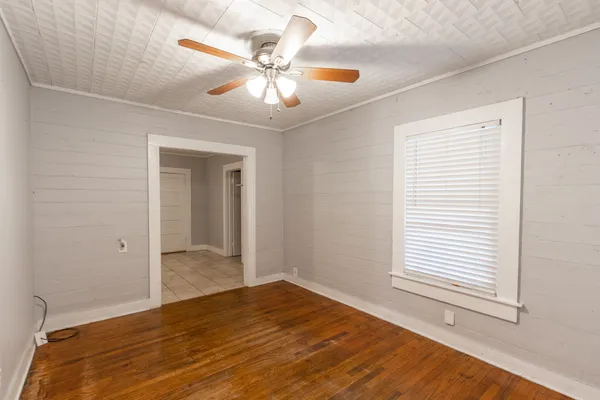 a view of an empty room with wooden floor and a window