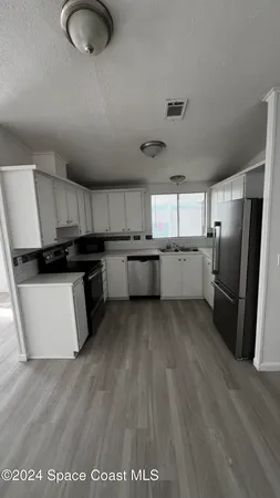 a kitchen with granite countertop a refrigerator stove top oven and sink