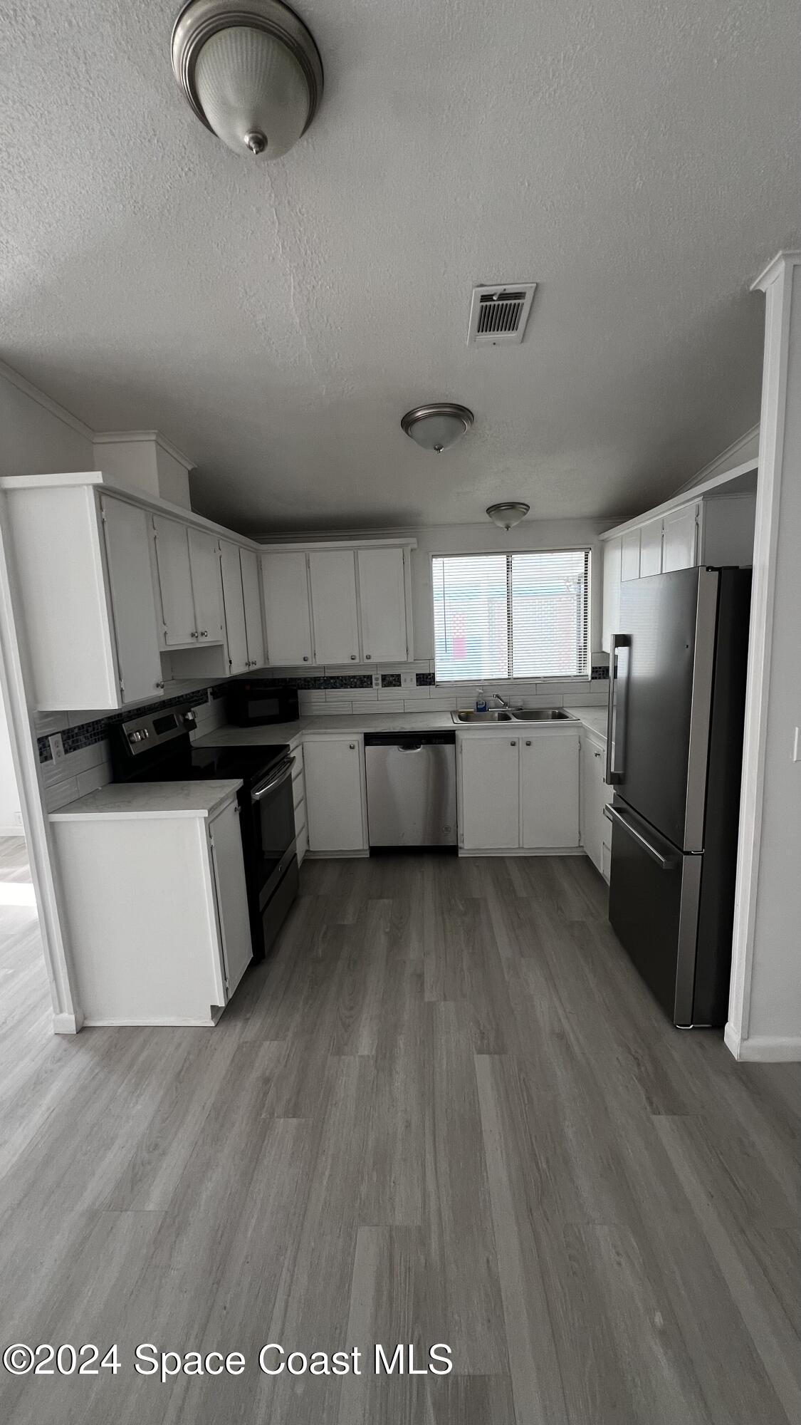 1972 Big Cypress Street Northeast Palm Bay, FL 32905 - Photo 3 of 7 a kitchen with granite countertop a refrigerator stove top oven and sink
