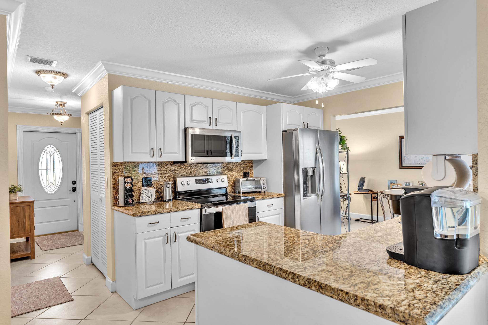 3106 Cormorant Road Delray Beach, FL 33444 - Photo 42 of 45 a kitchen with stainless steel appliances granite countertop a sink stove and refrigerator