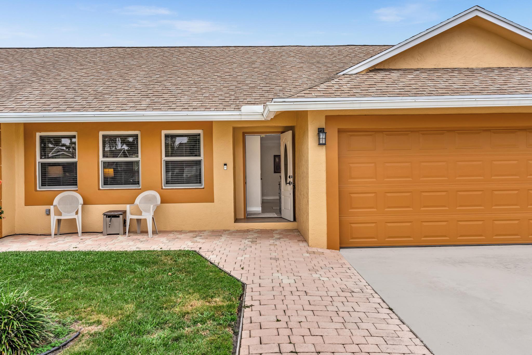 3106 Cormorant Road Delray Beach, FL 33444 - Photo 28 of 45 a front view of a house with glass windows and table