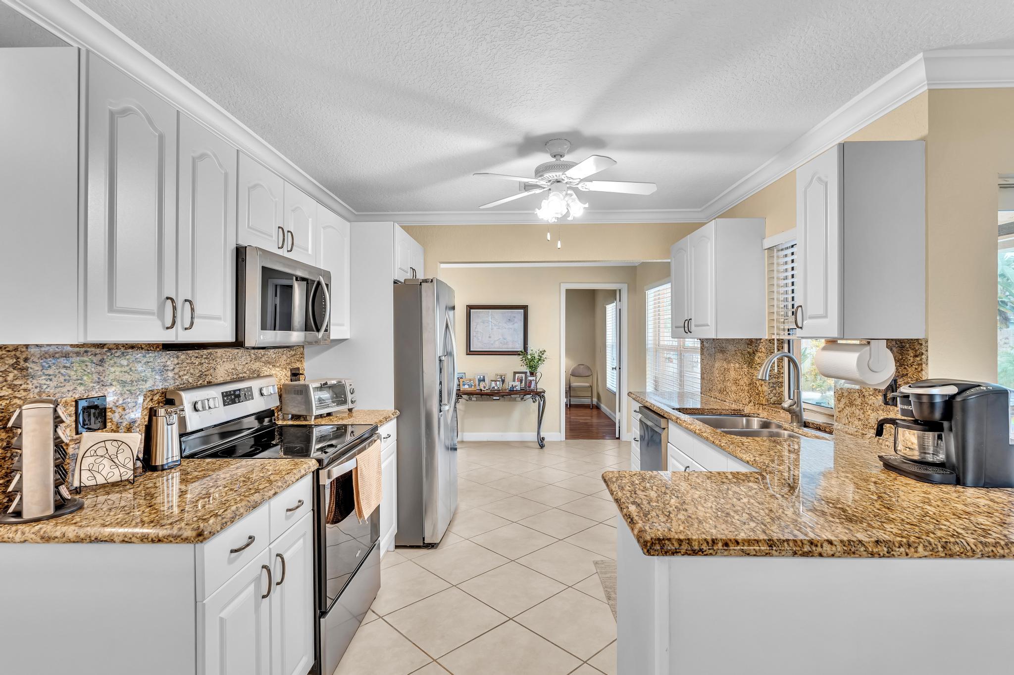 3106 Cormorant Road Delray Beach, FL 33444 - Photo 7 of 45 a kitchen with stainless steel appliances granite countertop a sink stove and cabinets