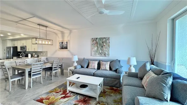 a living room with furniture kitchen view and a large window