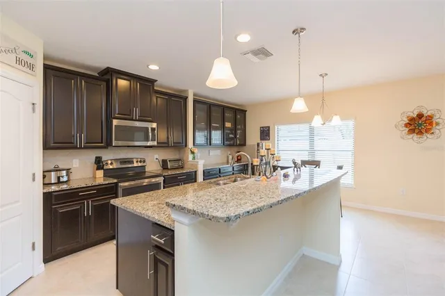a kitchen with kitchen island granite countertop a sink refrigerator and cabinets