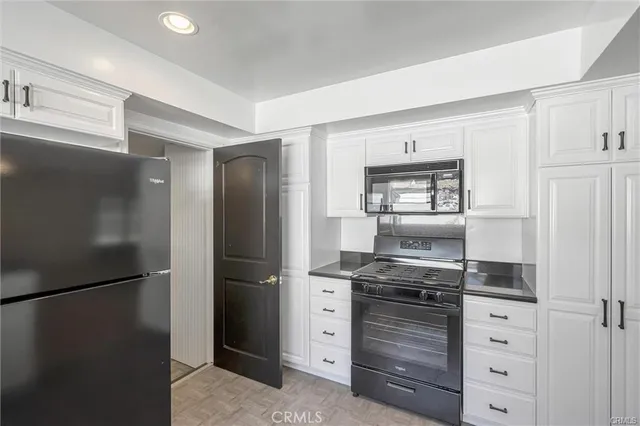 a kitchen with white cabinets and refrigerator